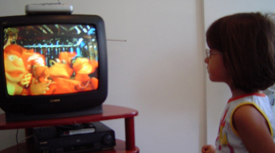 Menina assistindo Cocoricó na TV.