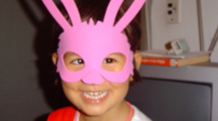 Menina com uma máscara rosa de coelhinho da Páscoa.