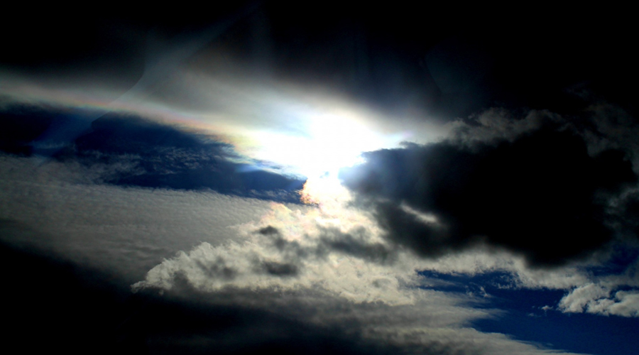 Imagem do céu com o sol saindo por entre as nuvens.