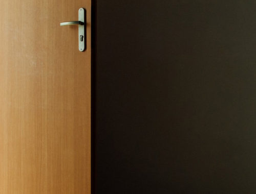 Foto de uma porta simples e madeira aberta.