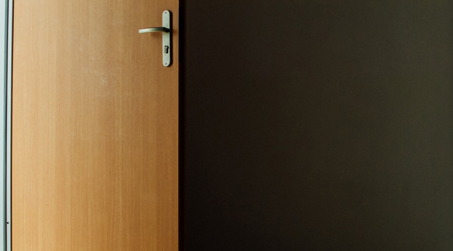 Foto de uma porta simples e madeira aberta.